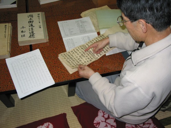 The Priest Mr. Kiyoshi Miyasaki pointing out some of the records on lake ice and the omiwatari. His data sheet summarizing the records are on the table. Photo taken Nov 3, 2005 by JJMagnuson.