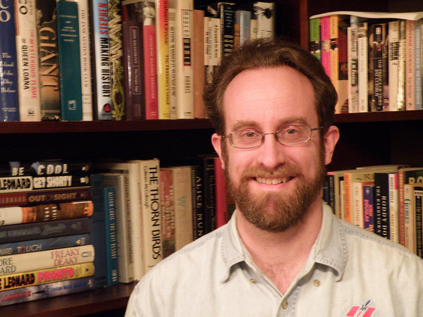 Patrick Hall in front of a bookcase full of books