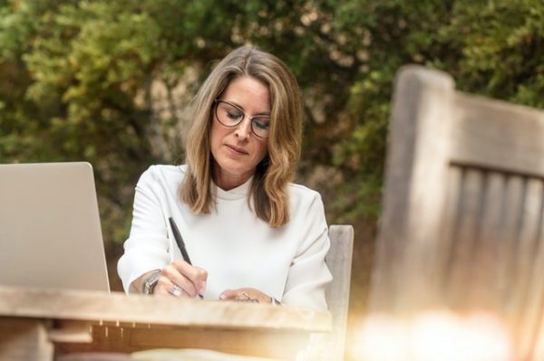 woman sitting at a table and writing 